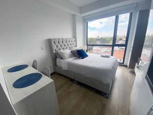 een slaapkamer met een bed en een groot raam bij Apartaestudios modernos y exclusivos en Bogotá in Bogota
