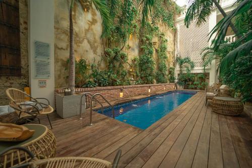 a swimming pool with chairs and a wooden deck at Cartagena Old City Mansion in Cartagena de Indias