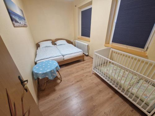 a small room with a crib and a bed and window at Familienfreundliche Fewo MV Malchin in Malchin