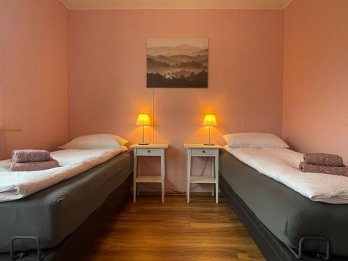 Dos camas en una habitación con dos lámparas. en Airport Comfort Home en Njarðvík