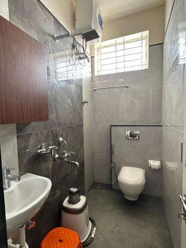La salle de bains est pourvue de toilettes blanches et d'un lavabo. dans l'établissement SanTrupthi A Stay at Home, à Chikmagalur