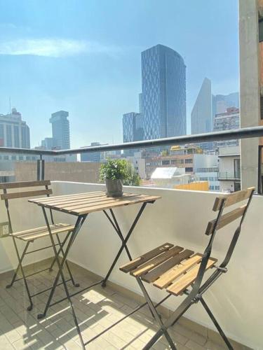 a table and chairs on a balcony with a view of a city at Asombroso Loft Moderno Con Excelente Ubicación in Mexico City
