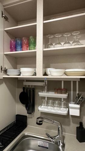 a kitchen with a sink and shelves with dishes at Elbon The beach Haeundae in Busan