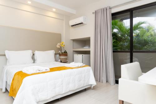a bedroom with a white bed and a large window at Hotel Palace 1 in Florianópolis