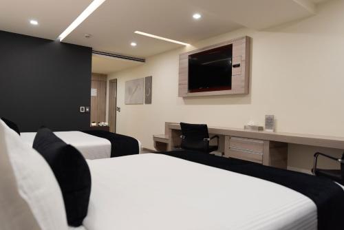 a hotel room with two beds and a desk and a tv at Domun Hotel in Querétaro