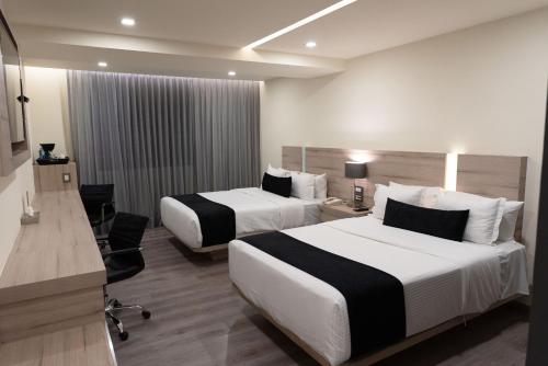 Habitación de hotel con 2 camas y escritorio en Domun Hotel en Querétaro