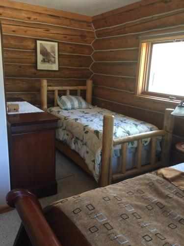 Valemount Mountain Retreat Guesthouse في فالماونت: غرفة نوم كابينة خشب بها سرير ونافذة
