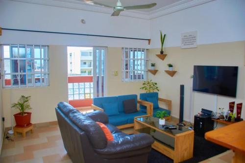 uma sala de estar com mobiliário azul e uma televisão de ecrã plano em Agim-Cotonou em Cotonou