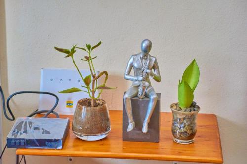 een tafel met een standbeeld en drie potplanten erop bij Agim-Cotonou in Cotonou