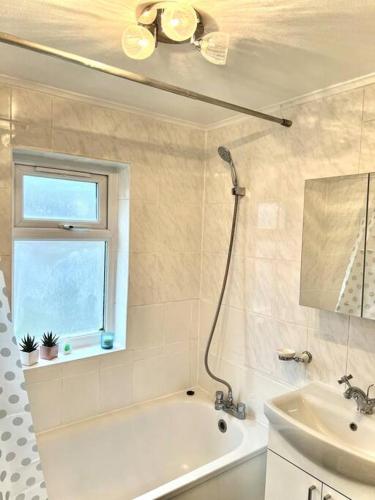 baño con bañera, lavabo y ventana en Holiday Home in Walthamstow, en Londres