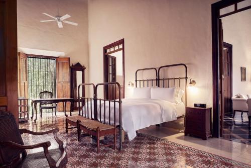 a bedroom with a bed and a chair and a mirror at Hacienda Temozon in Abalá