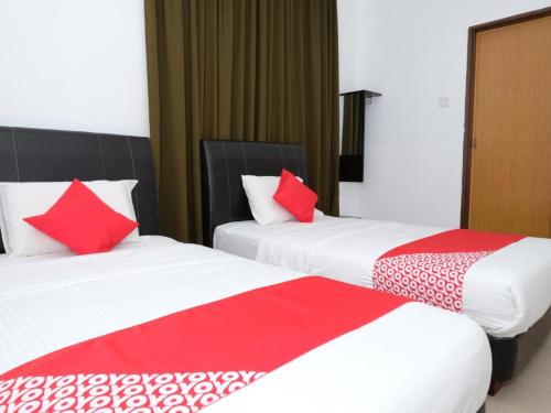 two beds in a hotel room with red and white pillows at Hotel De'light Villa in Kota Bharu