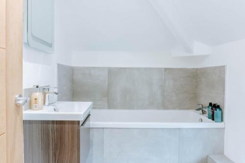 Baño blanco con lavabo y bañera en Spring Grove Apartment - Central Harrogate en Harrogate