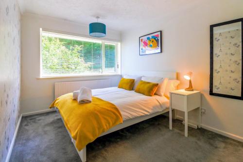 a bedroom with a bed with yellow sheets and a window at Airport Way - Cosy 2 Bed Apartment near the M1 in Luton