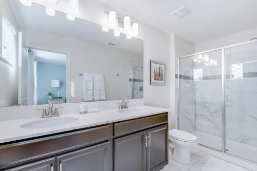 a white bathroom with two sinks and a shower at Luxury Home inside Champions Gate - No Extra Fees in Davenport