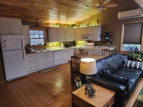 a living room with a black leather couch and a kitchen at 2 bed, 1.5 bath cottage across from Watauga Lake in Butler
