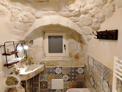 a stone bathroom with a sink and a toilet at Trulli Ritunno Piccolo in Locorotondo