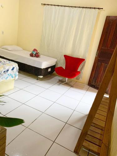 um quarto com uma cama e uma cadeira vermelha em Suite Apoena 1 em Pacoti