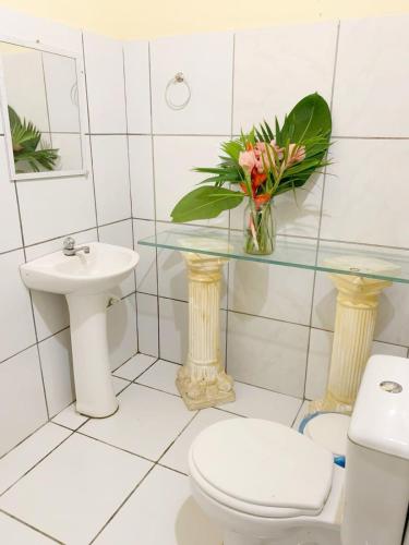 a bathroom with a toilet and a sink and a vase of flowers at Suite Apoena 1 in Pacoti