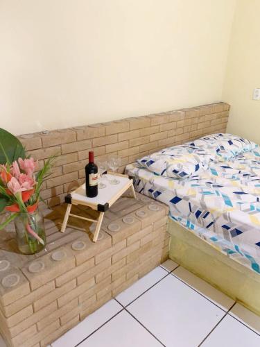 uma pequena cama com uma mesa com uma garrafa de vinho em Suite Apoena 1 em Pacoti