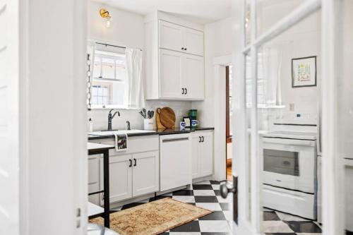 a kitchen with white cabinets and a black and white checkered floor at Downtown Bungalow with Geothermal Hot Spring in Boise