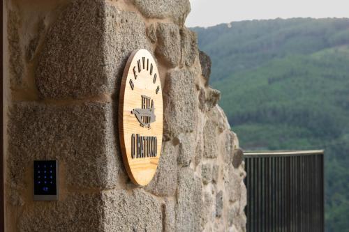 a wooden sign on the side of a stone wall at Ecolagar O Barqueiro in Pantón