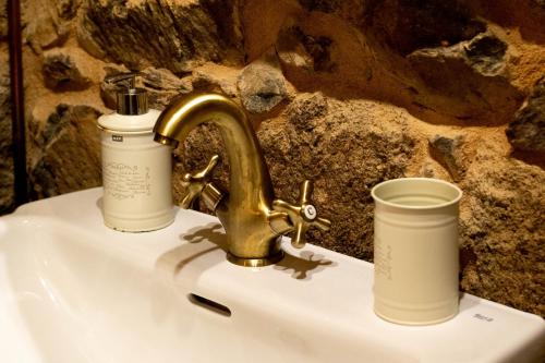 a sink with a faucet and two cups on it at Ecolagar O Barqueiro in Pantón