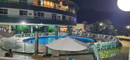 una piscina con sombrilla junto a un edificio en Angra inn Ap quarto e sala (temporadas), en Angra dos Reis