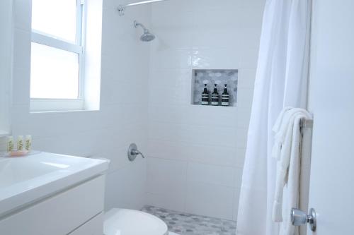 a white bathroom with a toilet and a sink at Sandpiper Apartments in Mount Pleasant