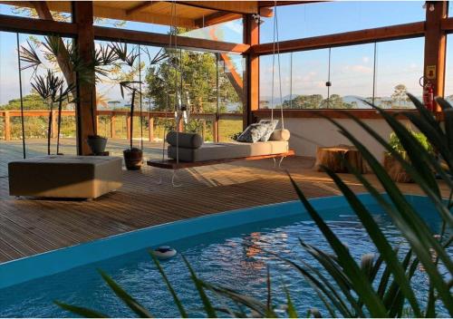 a living room with a swing over a swimming pool at Fazenda Santa Rita Turismo Rural in Bom Jardim da Serra