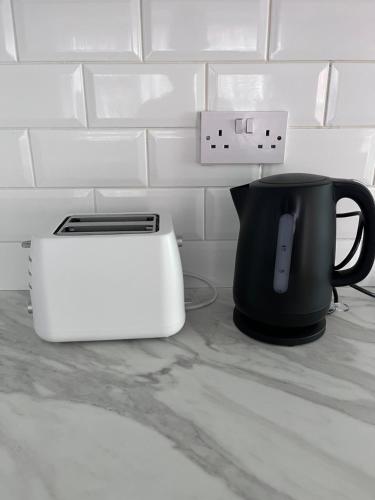 a black and white toaster and a black mug on a counter at Trendy Town house - Room 1 in Parkside