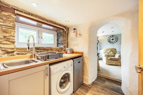 een keuken met een wastafel en een wasmachine bij Pendre Cottage in Llanfyrnach