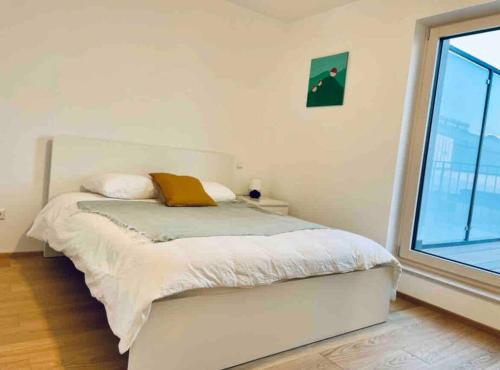uma cama branca num quarto com uma grande janela em Brand New 3 bedrooms with Terrace and Parking - 142-92 em Luxemburgo