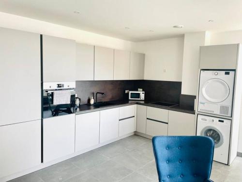 uma cozinha com armários brancos e uma cadeira azul em Brand New 3 bedrooms with Terrace and Parking - 142-92 em Luxemburgo