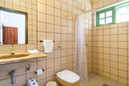 un bagno con un water, un lavandino e uno specchio di itamambuca condominio - Cabana Surf a Ubatuba