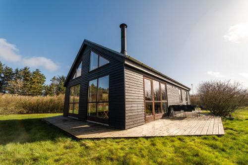 a small house with a deck in a field at Vidunderlig fritidshus ved Skov og Golfbane in Skjern