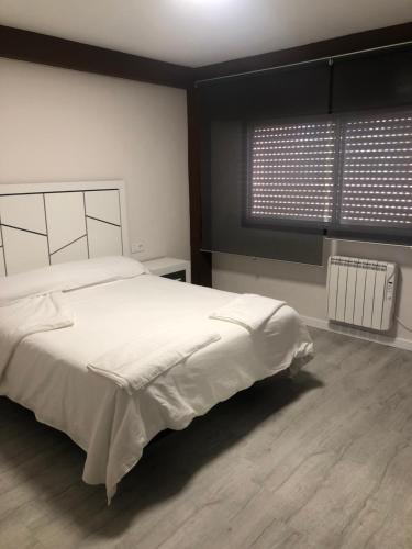 Un dormitorio con una gran cama blanca y una ventana en Piso Negreira, en Negreira