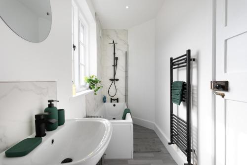 Baño blanco con bañera y lavamanos en Large 4 bed house Leicester, en Leicester