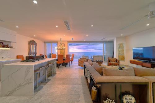 a living room with couches and a kitchen with a view at Maxwell Residences at Indah in Puerto Vallarta