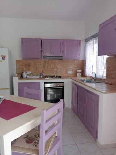 una cocina con armarios morados, fregadero y mesa en VIOLA, en Vila do Maio
