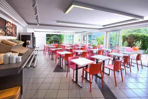 ein Restaurant mit roten Stühlen, Tischen und Fenstern in der Unterkunft Hôtel Formules Club 2 in Cenon