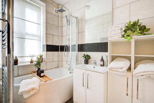 a bathroom with a tub and a sink and a shower at Beautiful 2bedroom close to Brick Lane in London