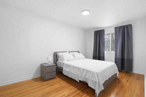 ein weißes Schlafzimmer mit einem Bett und einem Fenster in der Unterkunft Free Parking Gorgeous 3Bedrooms in Montreal