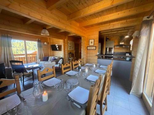 a dining room with a table and chairs and a kitchen at La joue du loup Bord des pistes - Chalet en bois de charme pour 10 personnes in Le Dévoluy