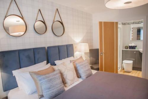 a bedroom with a bed with pillows and mirrors on the wall at Modern & central - two bedroom & two bathroom apartment in Bath