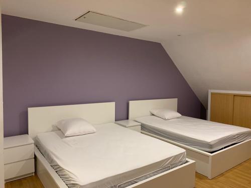 2 Betten in einem Zimmer mit lila Wänden in der Unterkunft IRIS 80 in Lorette