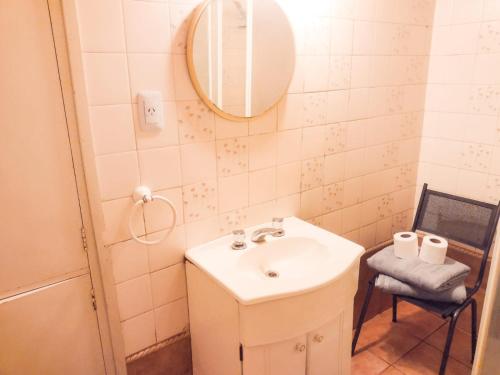 ein Badezimmer mit einem Waschbecken, einem Spiegel und einem Stuhl in der Unterkunft Lo de Juan in Godoy Cruz