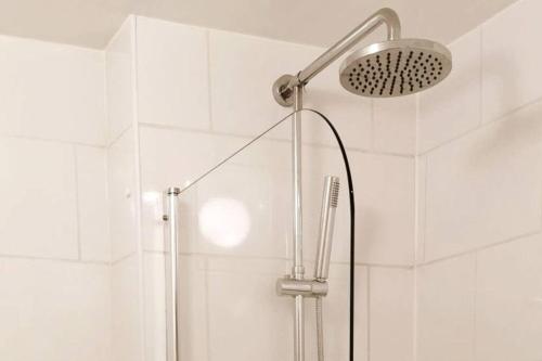 a shower with a shower head in a bathroom at Chy Lowen Private rooms with kitchen, dining room and garden access close to Eden Project & beaches in Saint Blazey