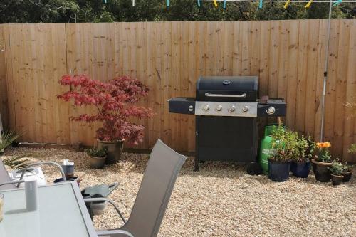a grill in a yard next to a wooden fence at Chy Lowen Private rooms with kitchen, dining room and garden access close to Eden Project & beaches in Saint Blazey