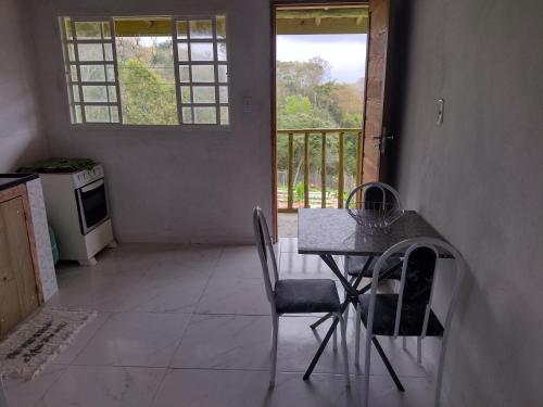 a kitchen with a table and chairs and a balcony at Chale 8A in Cunha